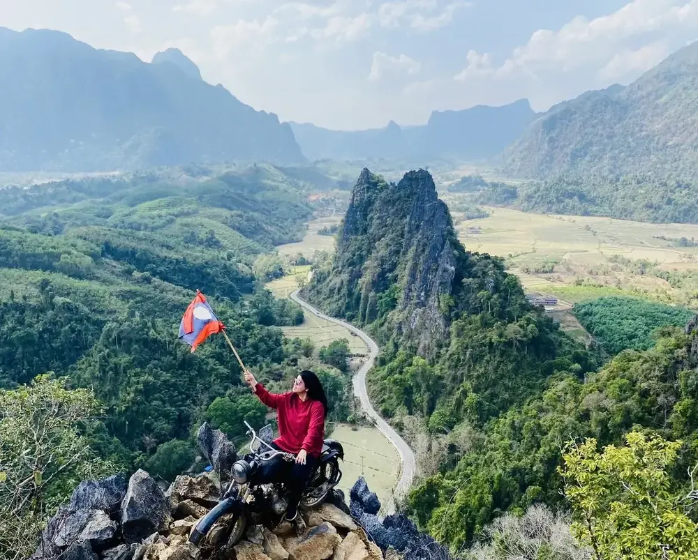 Afshana Diya waving the Laos flag from the Nam Xay viewpoint above Vang Vieng