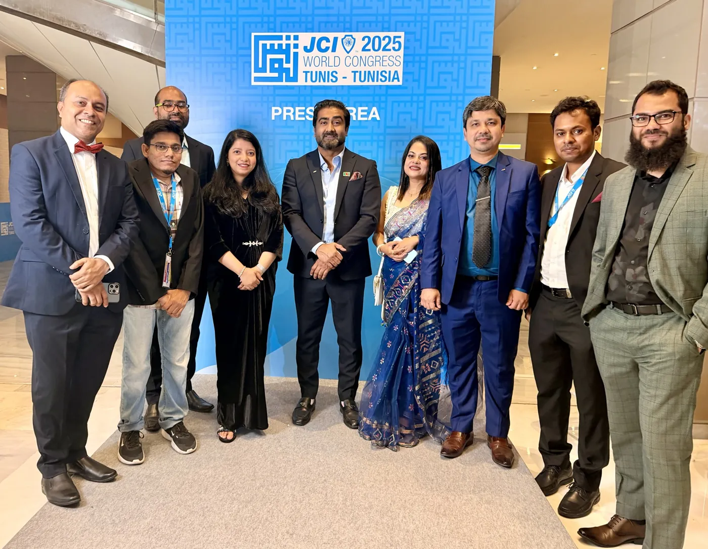 Afshana with friends in front of the JCI World Congress 2025 press wall