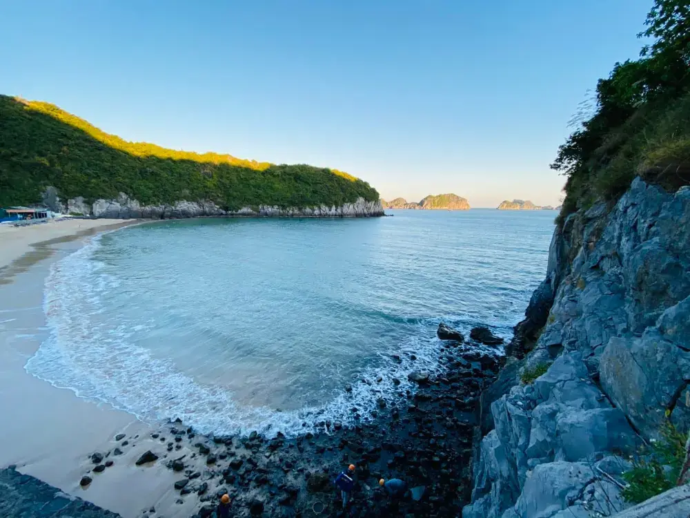 A quiet cove with a curved beach below a limestone cliff