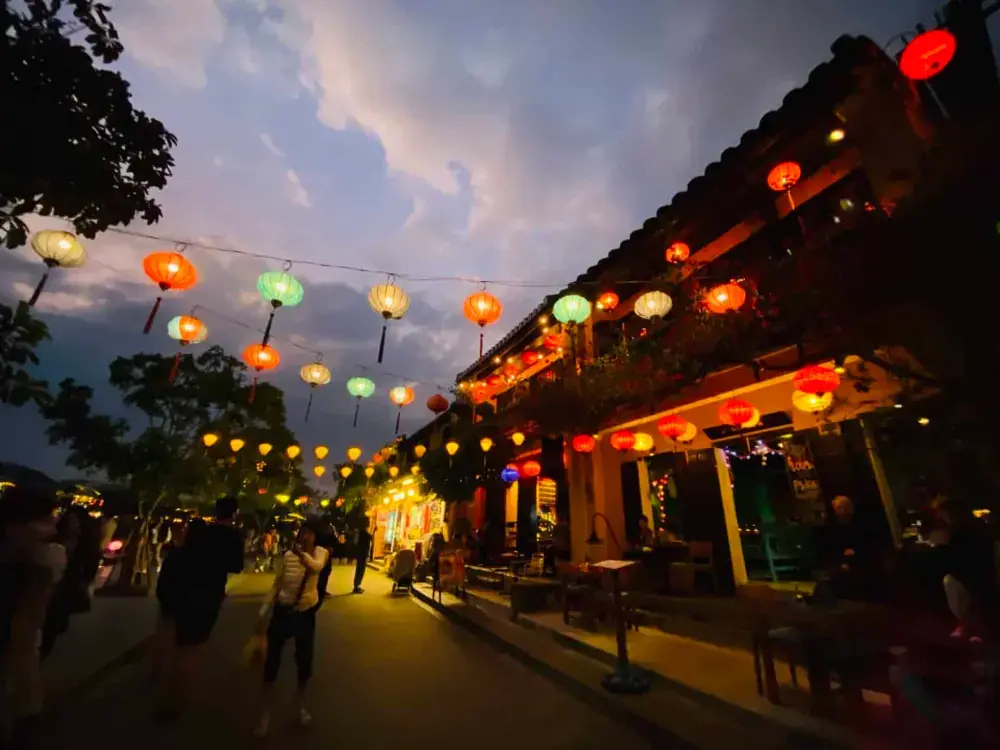 Old shophouses with lanterns along a street in Hoi An at dusk