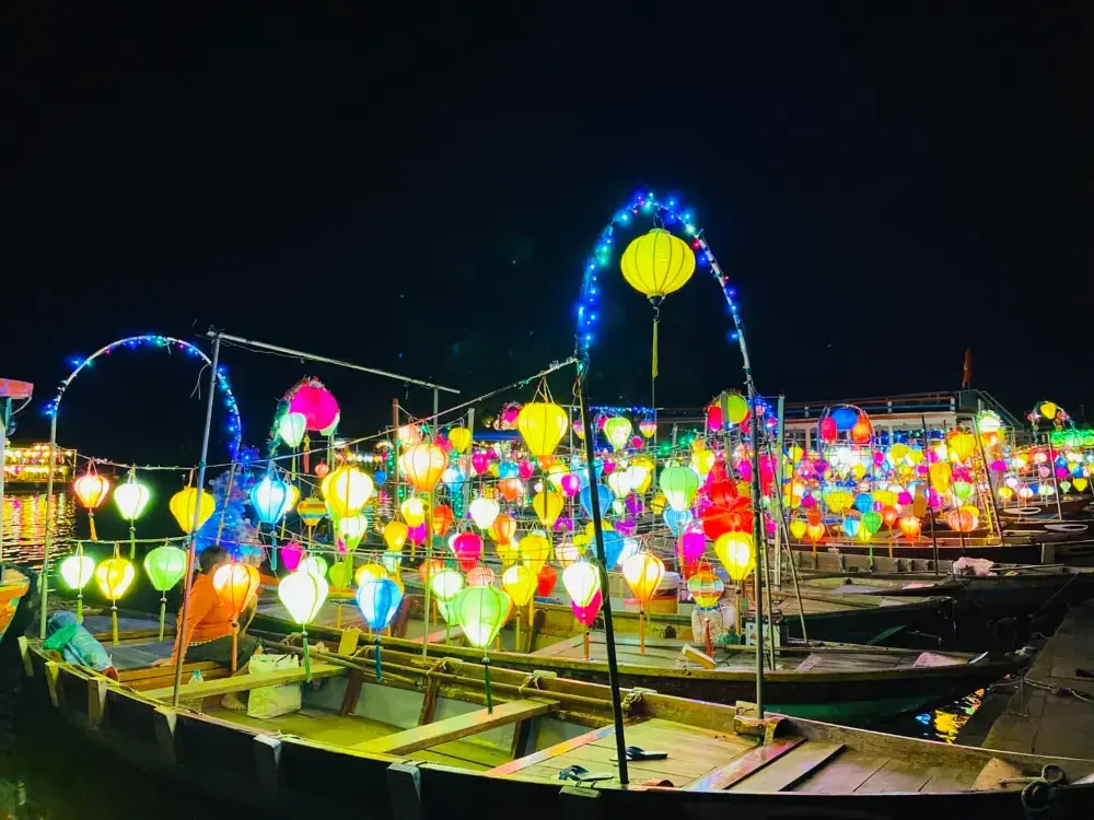 Wooden boats lit up with lanterns on the river at night