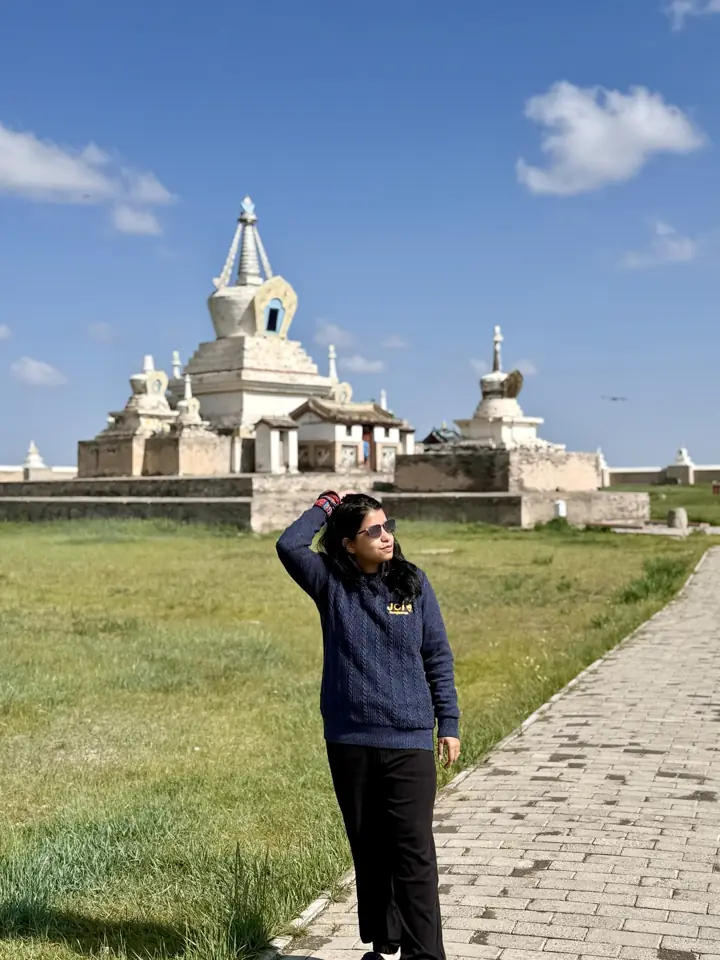Afshana Diya on a stone path in front of the white stupas of Erdene Zuu Monastery in Kharkhorin