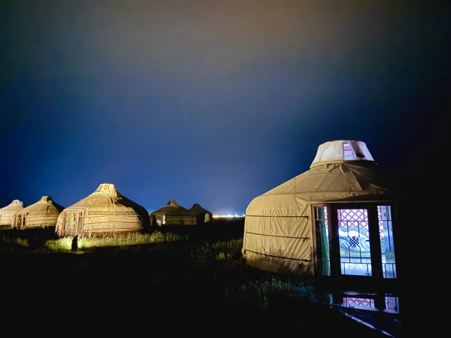 A Mongolian ger camp lit up at night under a dark blue sky
