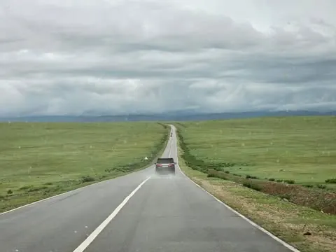 An empty road crossing green steppe west of Ulaanbaatar