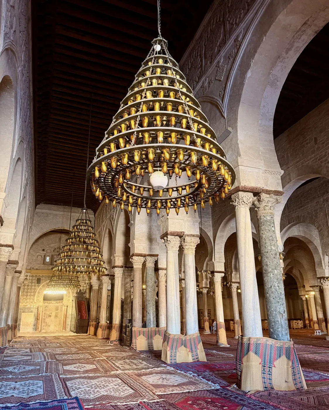 Chandeliers and marble columns inside the prayer hall of the Great Mosque of Kairouan