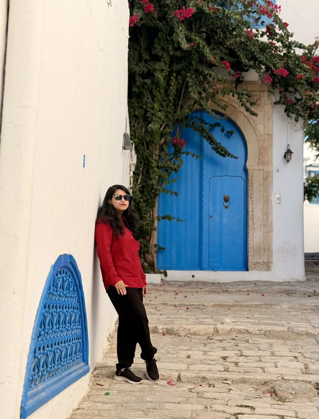 Afshana Diya in red beside a blue door in Sidi Bou Said