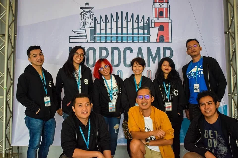 Afshana Diya with friends from the WordPress community in front of the WordCamp Iloilo 2019 backdrop