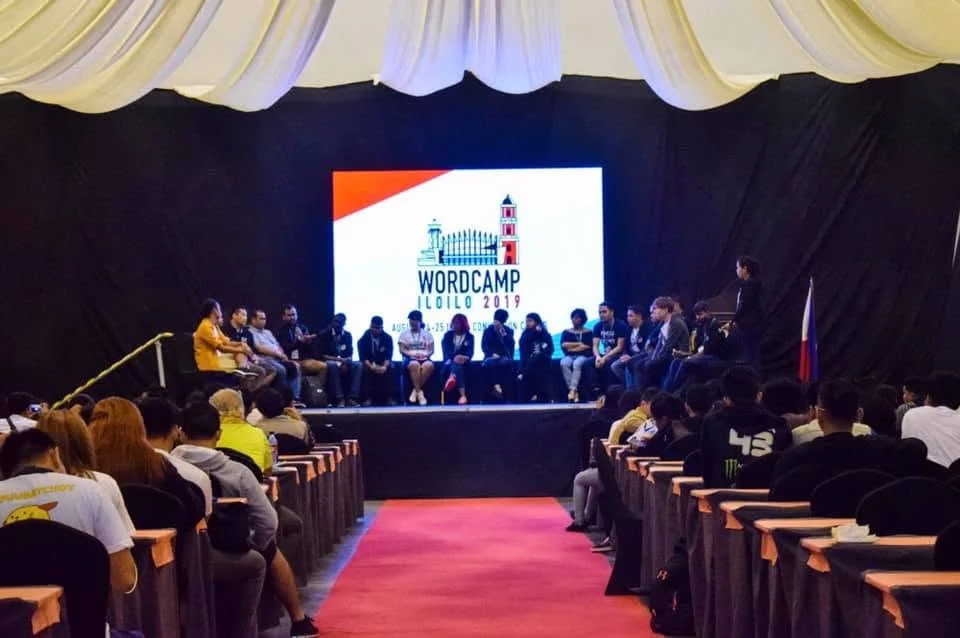 Speakers seated on stage under the WordCamp Iloilo 2019 screen